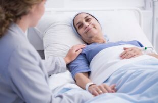 A healthcare professional providing compassionate end of life care to a patient resting in a hospital bed.