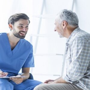 Healthcare professional in scrubs attentively interacting with an elderly man, fostering a compassionate and supportive environment.