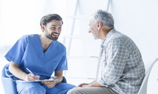 Healthcare professional in scrubs attentively interacting with an elderly man, fostering a compassionate and supportive environment.