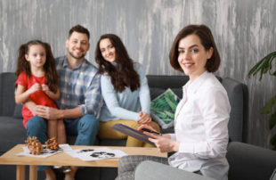 Family therapist conducting a counselling session with parents and child in a supportive family welfare setting.